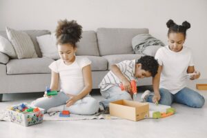 Children engaging in creative and educational activities at home, such as drawing, building with blocks, and doing simpl