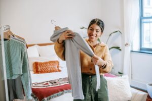 Rak pakaian kayu yang tersusun kemas dengan pakaian tergantung.