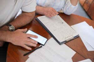 A man is carefully reviewing his monthly phone bill at a table, examining the details.