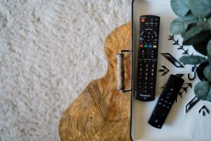Remote TV terselip di celah bantal sofa, menunjukkan masalah remote TV hilang.