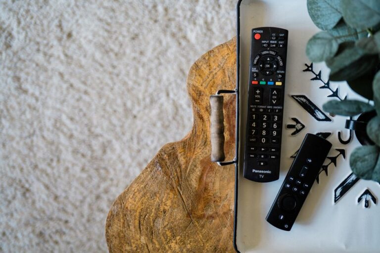 Remote TV terselip di celah bantal sofa, menunjukkan masalah remote TV hilang.
