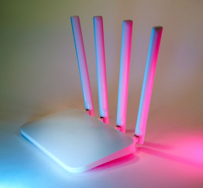 Orang sedang melihat skrin komputer riba yang memaparkan halaman web lambat, dengan router WiFi di latar belakang.